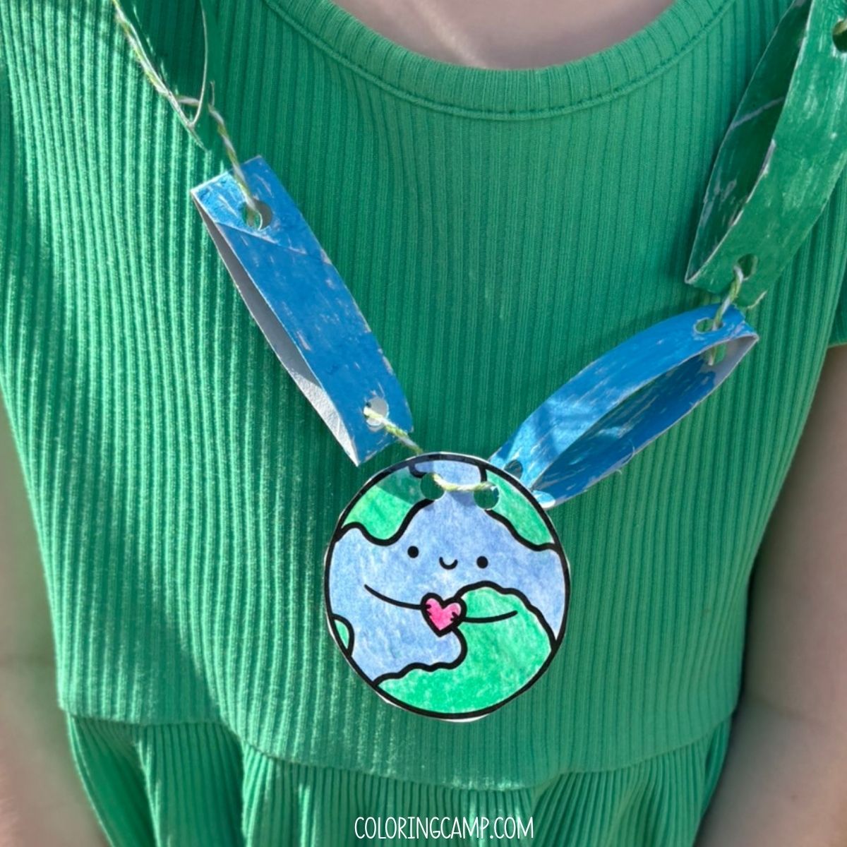 A child holding their Earth Day Necklace craft.