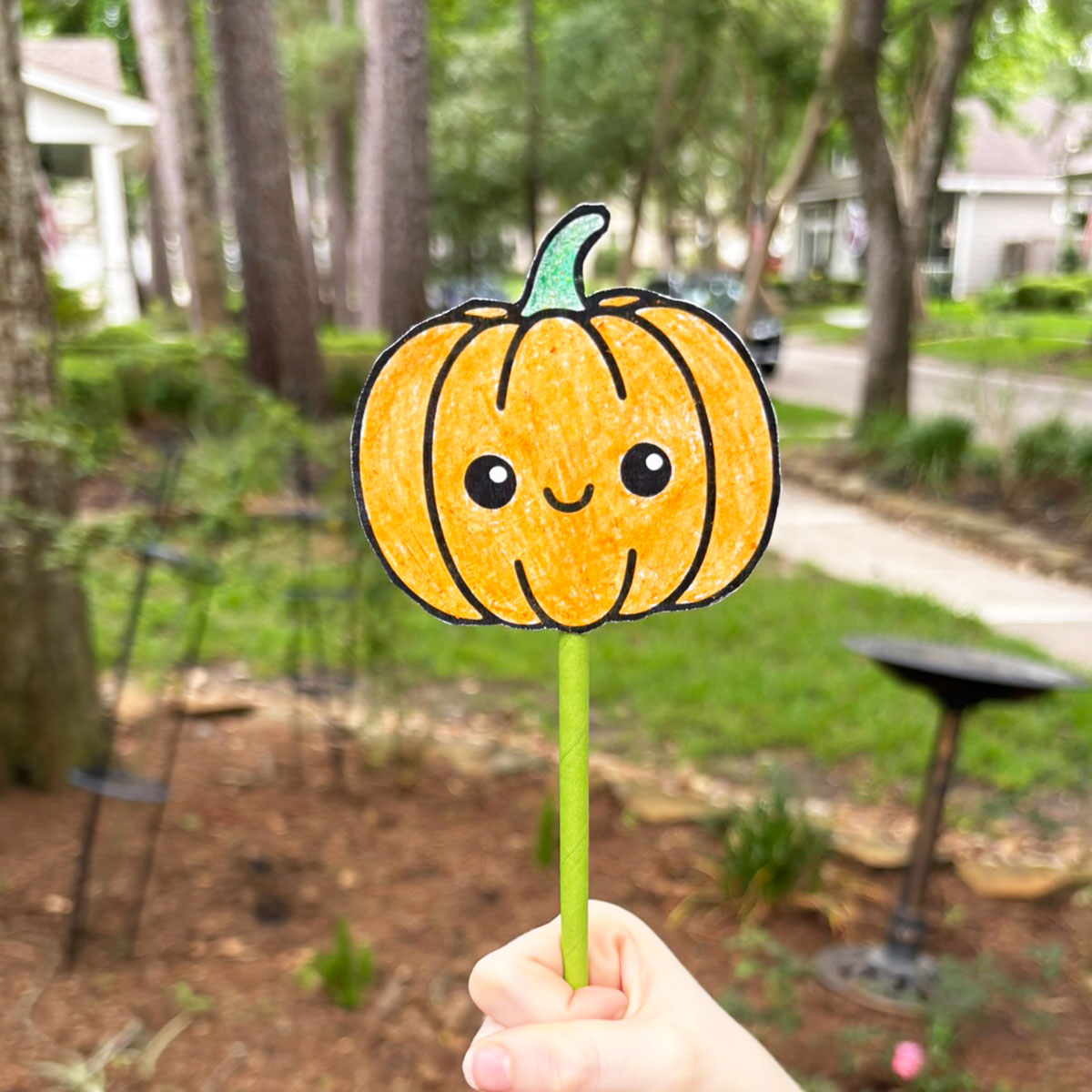 A child's hand holding a fall wand craft.